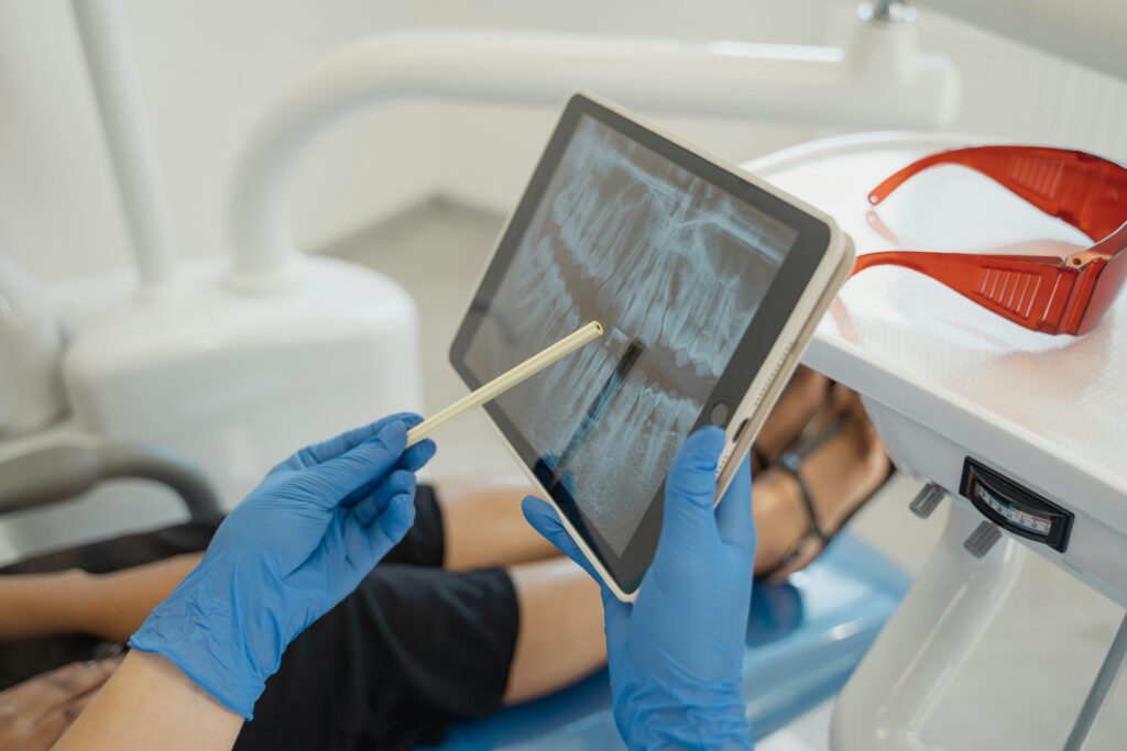 Dentist showing dental x-ray on tablet to patient in a modern clinic setting.